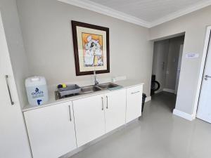 a kitchen with white cabinets and a sink at Central, Beachfront Home in Jeffreys Bay +8 photos