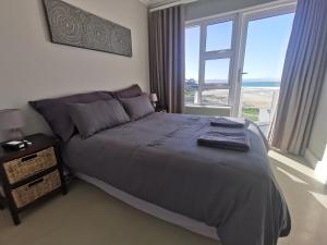 a bedroom with a bed and a large window at Central, Beachfront Home in Jeffreys Bay