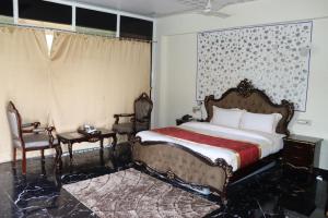 a bedroom with a bed and two chairs and a window at arham farm in Jāmb +1 photo