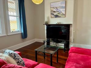 ein Wohnzimmer mit einem roten Sofa und einem Fernseher in der Unterkunft The Gregory in Geraldton