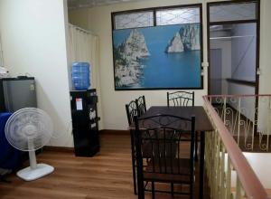a dining room with a table and chairs and a fan at HOM's HOSTEL in Phuket