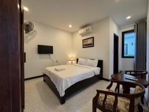 a bedroom with a bed and a table and a television at La Me Villa Hoi An in Hoi An