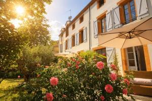 a building with an umbrella and flowers in a yard at Le RELAIS in Lézat-sur-Lèze