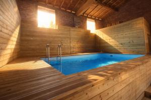 a large swimming pool in a wooden house with a wooden floor at Le RELAIS in Lézat-sur-Lèze