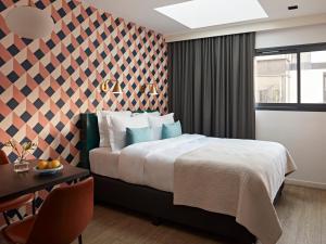 a hotel room with a bed and a desk and a window at YAYS Paris Issy by Numa in Issy-les-Moulineaux