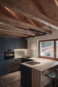 a kitchen with wooden ceilings and a kitchen island with a sink at Deluxe Apartments Lantl in Falzes