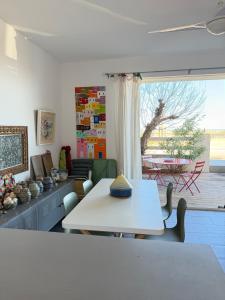 a living room with a white table and a window at Vue Mer - appartement de charme - accès direct plage in Leucate-Plage