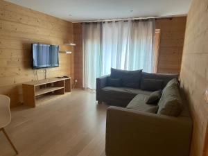 a living room with a couch and a flat screen tv at ANNEXE 1888 in Magland