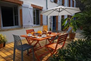a wooden table with chairs and an umbrella at Le RELAIS in Lézat-sur-Lèze