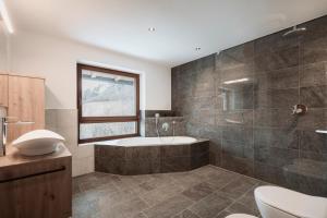 a bathroom with a tub and a toilet and a window at Deluxe Apartments Lantl in Falzes +38 photos