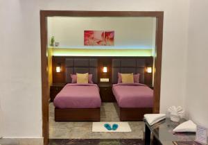 a bedroom with two beds with purple sheets and a mirror at Solitude, The Boutique Hotel- Ultra Luxurious in Haldwāni