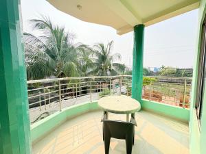 a balcony with a table and a view of palm trees at Manas Kanya Mandarmani Hotel & Restaurant - Swimming Pool - Banquet - Parking Facility Full AC Room in Mandarmoni
