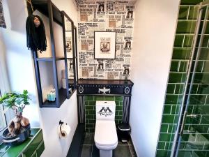 a bathroom with a toilet and a green tiled wall at Ricky Road Guest House in Watford +52 photos