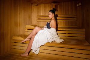 a woman sitting in a sauna wearing a dress at Hotel Sella Ronda Serenella - A 50 mt dalle piste da sci in Campitello di Fassa