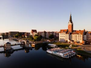 a city with a river with boats in the water at Apartamenty przy parku in Elblag