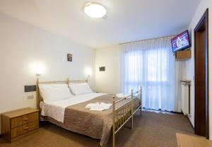 a bedroom with a bed and a flat screen tv at Hotel Sella Ronda Serenella - A 50 mt dalle piste da sci in Campitello di Fassa