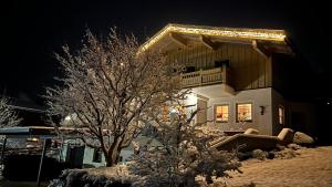 a house with a tree in the snow at night at Tauernchalet-S'Hoamatl in Hollersbach im Pinzgau
