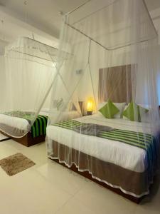 a bedroom with two beds with mosquito nets at Cloudy Hill Cottage in Ella