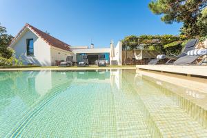a swimming pool with chairs and a house at Villa Santamaria in Colares