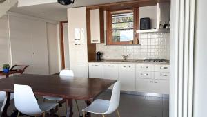 a kitchen with a wooden table and white chairs at Refugio Azul Baveno, pool and private parking in Baveno