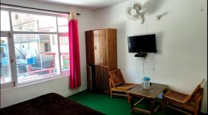 a room with a table and a tv and a window at Apple Garden Aleo in Manāli