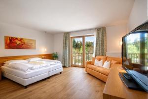 a bedroom with a bed and a couch and a television at Garden Park Hotel in Prato allo Stelvio