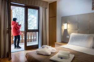a person looking out the window of a bedroom at Hotel Sella Ronda Serenella - A 50 mt dalle piste da sci in Campitello di Fassa