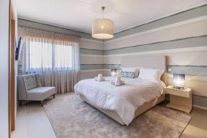 a bedroom with a large bed and a chair at Villa del Rey II in Casal da Lagoa Seca +33 photos