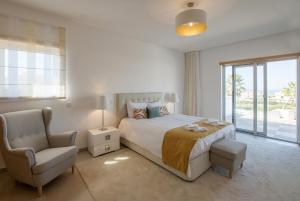 a bedroom with a bed and a chair and a window at Villa del Rey III in Casal da Lagoa Seca +27 photos