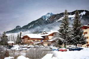 a ski lodge with cars parked in the snow at Hotel Sella Ronda Serenella - A 50 mt dalle piste da sci in Campitello di Fassa
