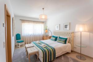 a bedroom with a bed and a blue chair at Villa del Rey VIII in Casal da Lagoa Seca
