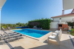 a swimming pool with chaise lounge chairs next to a house at Villa del Rey VII in Casal da Lagoa Seca