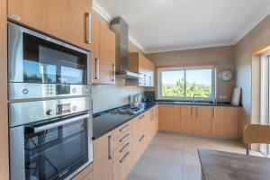 a kitchen with wooden cabinets and a stainless steel appliance at Villa del Rey VII in Casal da Lagoa Seca
