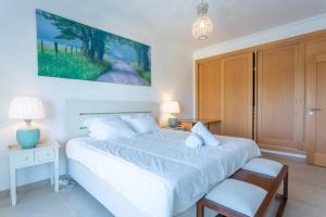 a bedroom with a white bed and a table and chair at Villa del Rey VII in Casal da Lagoa Seca +29 photos