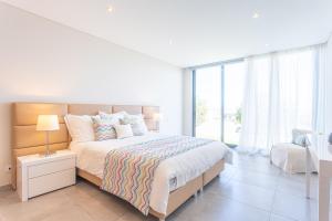 a white bedroom with a bed and a large window at Villa Sao Martinho in São Martinho do Porto +24 photos