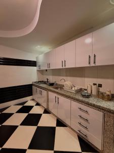 a kitchen with white cabinets and a black and white checkered floor at Charming Bohemian hideaway in Marrakech in Marrakesh