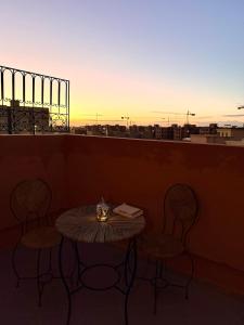 a table and chairs on a balcony with the sunset at Charming Bohemian hideaway in Marrakech in Marrakesh +16 photos