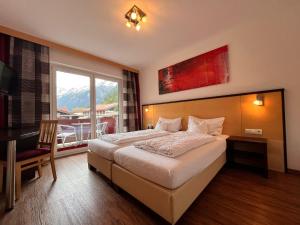 a hotel room with a bed and a large window at Sporthotel Bergheim in Sölden