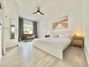 a white bedroom with a white bed and a living room at Chalet JULI Mirador in Puerto de la Cruz