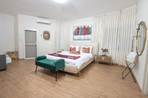 a bedroom with a large bed and a green chair at וילה ריש - וילה מהממת למשפחות עם חמאם תורכי במתחם, ממ"ד ובריכה פרטית in Yarka