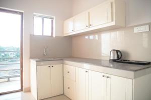 a kitchen with white cabinets and a sink and a window at Gentur Enclave in Mananthavady