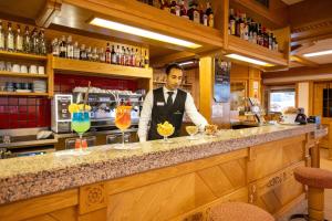 a man standing behind a bar with some cocktails at Hotel Sella Ronda Serenella - A 50 mt dalle piste da sci in Campitello di Fassa +47 photos