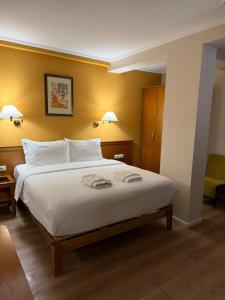 a bedroom with a large white bed with yellow walls at Arber Hotel in Tirana +19 photos