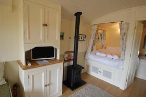 a room with a fireplace and a tv and a bedroom at Le Grande Roulotte in Hassocks
