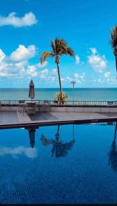 a swimming pool with a palm tree and the ocean at ONDINA SSA in Salvador