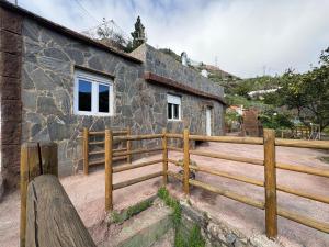 a house with a wooden fence next to a building at El Refugio de Juncalillo in Gáldar
