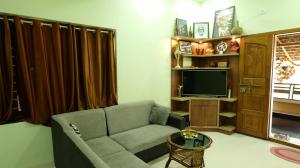 a living room with a couch and a television at Atharvam Resort in Cherai Beach