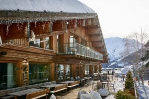 a wooden building with tables and chairs in the snow at Chalet Morel 1586 Hotel & Spa in Limone Piemonte