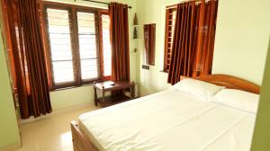 a bedroom with a white bed and a window at Atharvam Resort in Cherai Beach