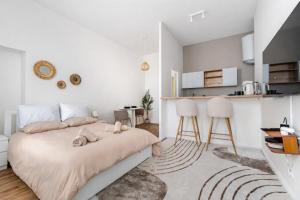 a white bedroom with a large bed and a kitchen at Charmant Studio Cosy - Hyper-Centre D'Elbeuf in Elbeuf
